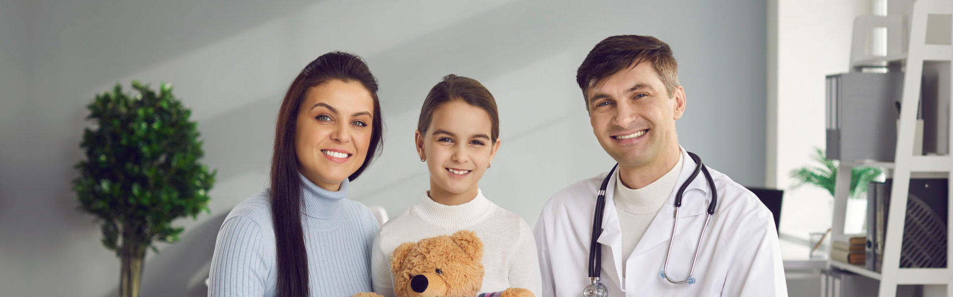 Happy parent and kid trust their doctor. Portrait of smiling mother, child and family practitioner. Mum, daughter with teddy bear, and friendly pediatrician with stethoscope looking at camera together
